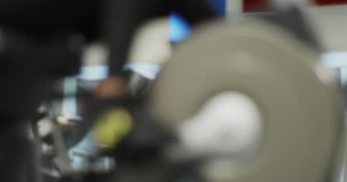 Kadın spor salonunda eliptik çapraz antrenörle egzersiz yapıyor. Yan görüş, pedal çevirme, ağır çekim. Eliptik bisiklette kadın eğitimi. Spor salonunda pedal çeviren kadın.