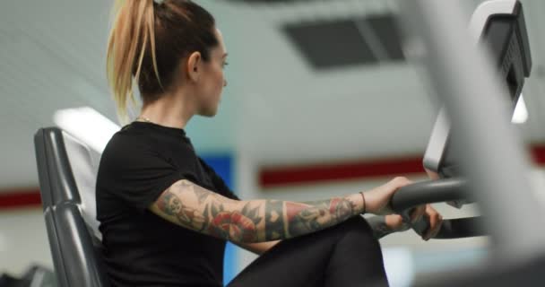 Vrouw die traint met een crosstrainer in de gym.Bekijk close-up, slow motion. Vrouwentraining op een crossmotor. Vrouw aan het trappen in de sportschool — Stockvideo