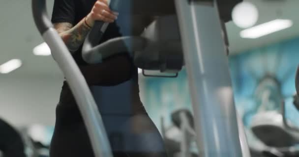 Žena cvičení s eliptickou chůzi stroj na gym.Front view, zpomalení. Trénink žen v chodícím stroji. Žena kráčející po posilovně — Stock video