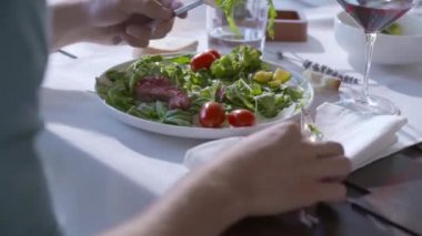 Izgara etle karışık salata yiyen birinin ayrıntıları. Eller yakın çekimde..