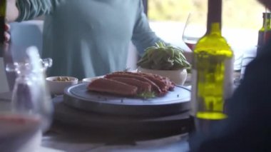 Et ızgara taşında pişiyor. İnsanlar evde birlikte yemek yiyor.
