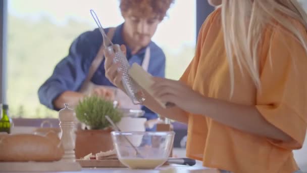 Hombre cocinar y comprobar la comida en la cocina moderna.Mujer agarrando cheese.Young pareja cocinar y preparar la comida para el almuerzo o la cena en casa. Cocina moderna de espacio abierto — Vídeo de stock