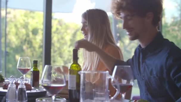 Чоловік і жінка розмовляють разом під час обіду вдома. Люди їдять їжу, п'ють вино. — стокове відео