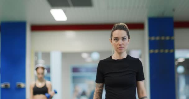 Mujer descansando durante el entrenamiento en el gimnasio.Mujer cansada relajándose durante el descanso de fitness. Vista frontal, plano medio — Vídeo de stock