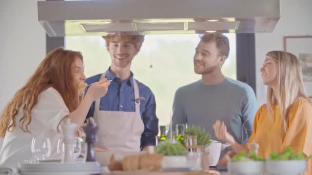 Čtyři lidé spolu při vaření doma v moderní kuchyni.Mladí lidé vaří a připravují jídlo k obědu nebo večeři. Moderní domácí open space kuchyně — Stock video