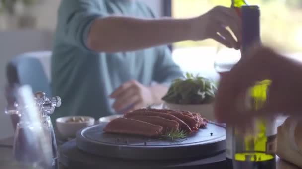 Detalle de la cocción de la carne en piedra de parrilla. Gente comiendo juntos en casa — Vídeos de Stock