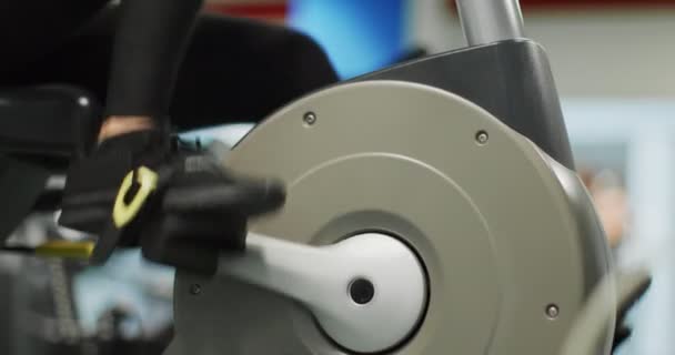 Donna che si allena con crosstrainer in palestra Vista laterale, dettaglio sulla pedalata delle gambe, rallentatore. Allenamento femminile su bici ellittica. Donna che pedala in palestra — Video Stock