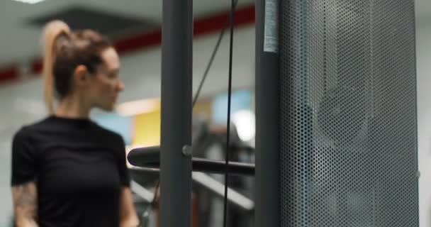 Женщина тренируется с кабелем трицепс бар на gym.Rear зрения, замедленная съемка. Женщина тренируется в трицепс отжимания машины — стоковое видео