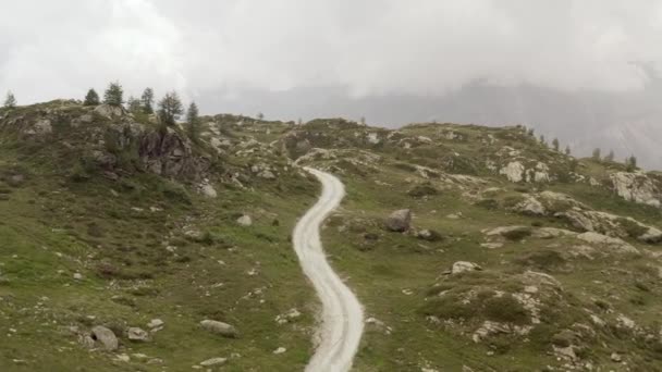Cinematic aerial view gravel trail road on the mountain. Cloudy weater, mist and haze. Forward dolly — Stock Video