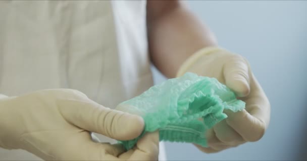 Dokter in beschermend pak en handschoenen met pet op. Verpleegster in beschermend pak met handschoenen met dop dicht. Vrouw met beschermkap — Stockvideo