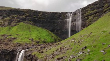 Faroe Adaları 'ndaki çarpıcı şelalenin havadan görünüşü. Fossa şelalesinin havadan görünüşü. Hava bulutlu, çekim yapıyoruz, insan yok. Vahşi kayalık yamaçta görkemli bir şelale. Yüksek kaliteli görüntüler.