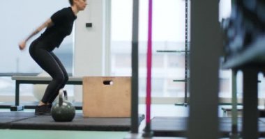 Spor salonunda kutuya atlayan bir kadın. Kadın bacakları eğitimi. Ön görüş MS, yavaş çekim. Fitness kardiyo aktivitesi. Spor salonunda kadın eğitimi