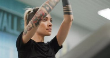 Spor salonunda koşu bandında gerinen genç bir kadın. Ön manzara yakın çekim, üst vücut detayı. Spor salonunda kadın eğitimi. Kardiyo egzersizi yapan kadın.