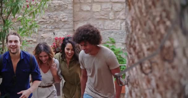 Cuatro personas felices caminando juntas por las escaleras de una ciudad. Cuatro turistas visitando la ciudad rural italiana. Cuatro amigos caminando por la estrecha calle de la ciudad . — Vídeo de stock