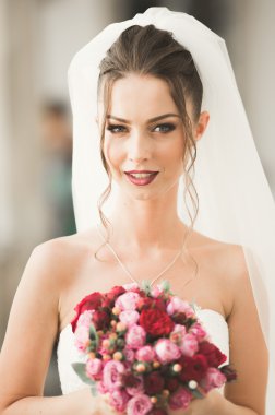 Lüks bir gelin, bir kız buketle poz veriyor ve gülümsüyor.