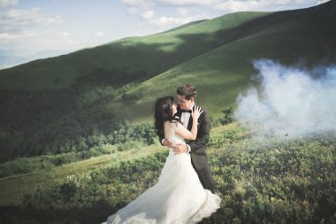 Güzel bir düğün çifti mükemmel bir manzarayla dağda öpüşüyor ve sarılıyor.