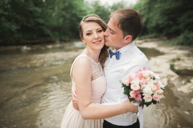 Zarif nazik şık damat ve gelin taşlarla Nehri yakınında. Evlilik çift aşık