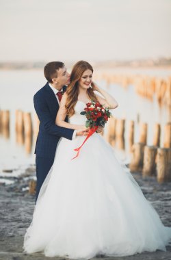 Güzel genç düğün çift, gelin ve damat arka plan denizde ahşap direklerin yakın poz