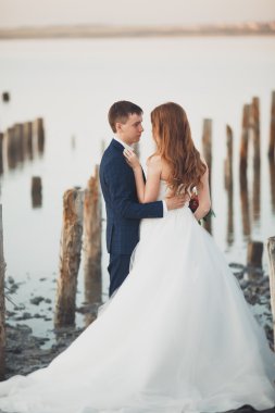 Çift düğün, damat, gelin buketi günbatımı üzerinde denize yakın poz ile