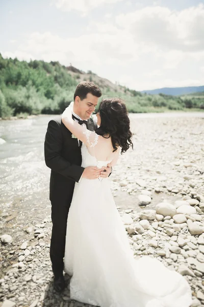 Sposa e sposo in possesso di bel bouquet da sposa. Posa vicino al fiume — Foto Stock