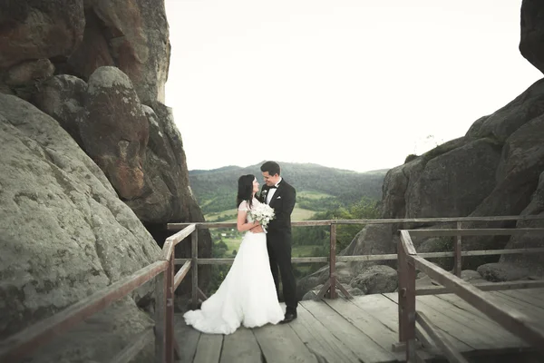 Couple de mariage heureux embrasser et étreindre près d'une haute falaise — Photo