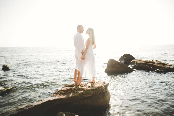 Casamento casal apenas andando na praia ao pôr do sol . — Fotografia de Stock