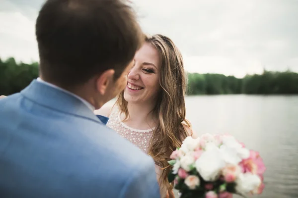 Счастливой свадьбы пара обнимает и улыбается друг другу на заднем плане озера, леса — стоковое фото