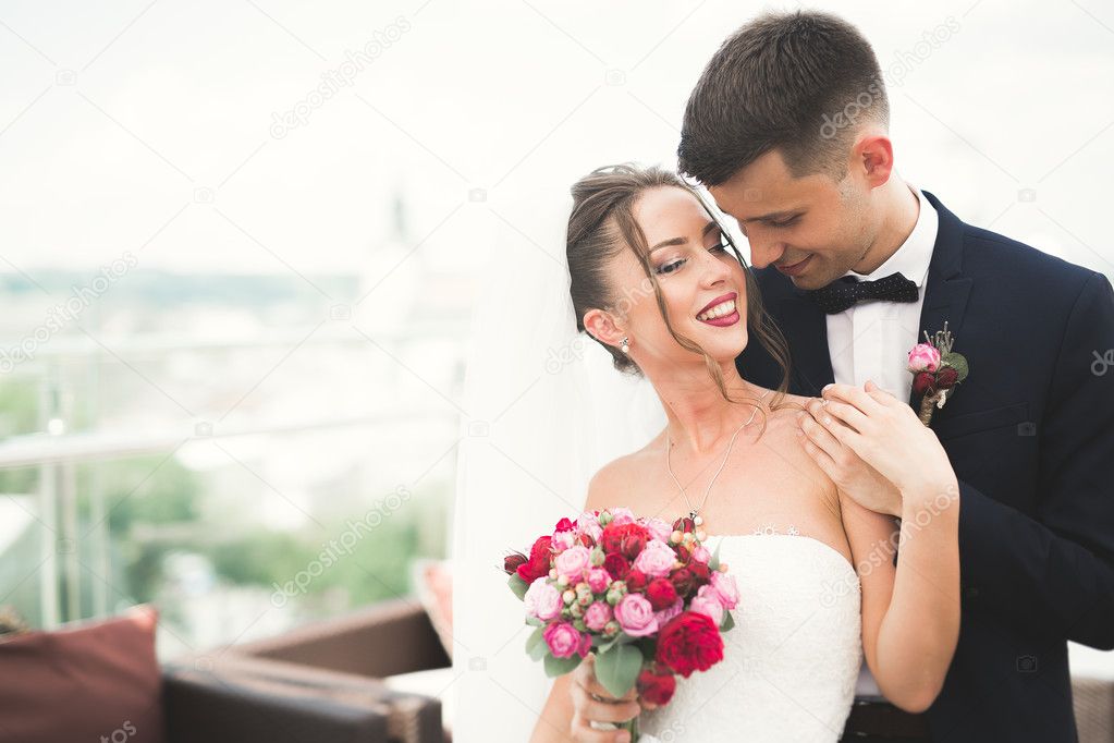 Beautiful couple, bride and groom posing on balcony with backgrounf of old city