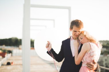 Çatıda mükemmel şehir manzaralı elele ve sarılma poz aşık genç bir çift. Güzel gün batımı