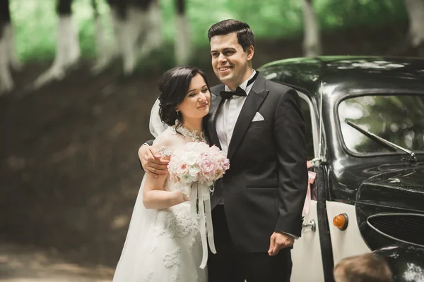 Şık düğün çift, Gelin, damat öpüşme ve retro arabanın yakınında sonbaharda sarılma