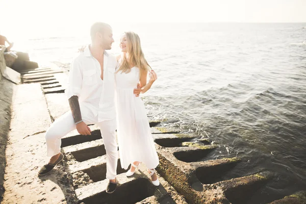 Romantica coppia amorevole posa su pietre vicino al mare, cielo blu — Foto Stock