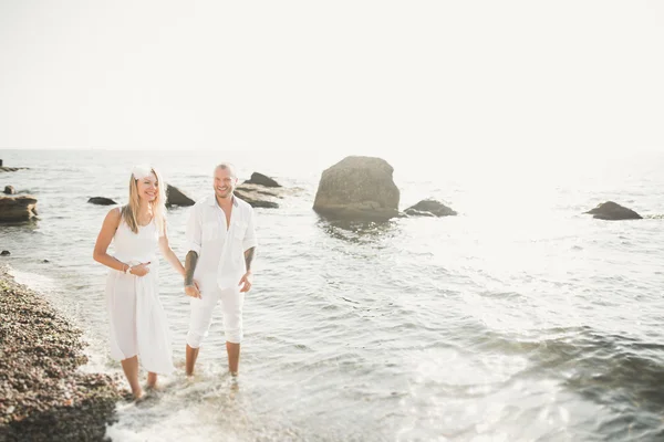 Casamento casal apenas andando na praia ao pôr do sol . — Fotografia de Stock