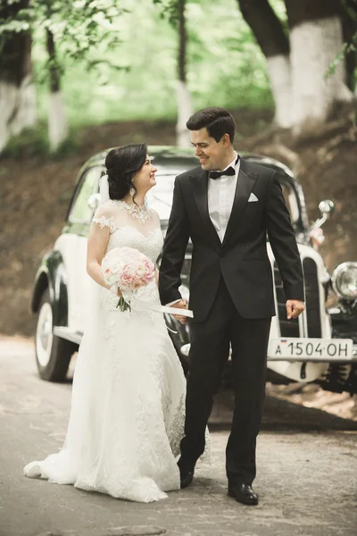 Hermosa pareja de boda posando cerca de espléndido coche retro Fotos De Stock