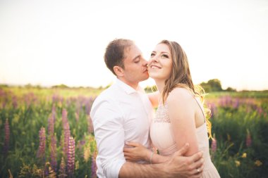 Gelin ve damat, çiçekler, güzel bir alanda gün batımında rissing romantik evli çift