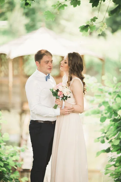Krásný pár v lásce líbat navzájem na svatební den, stojící v parku venku u jezera — Stock fotografie