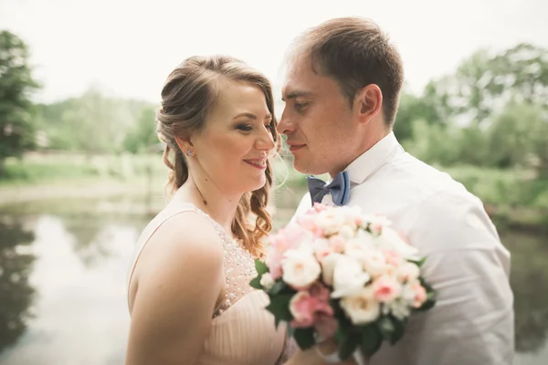 Novia y novio celebrando hermoso ramo de bodas. Lago, bosque —  Fotos de Stock