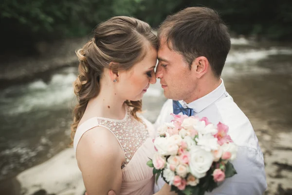 Νύφης και του γαμπρού κρατώντας όμορφη γαμήλια ανθοδέσμη. Λίμνη, δάσος — Φωτογραφία Αρχείου