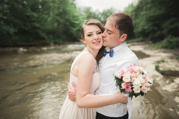 Zarif nazik şık damat ve gelin taşlarla Nehri yakınında. Evlilik çift aşık