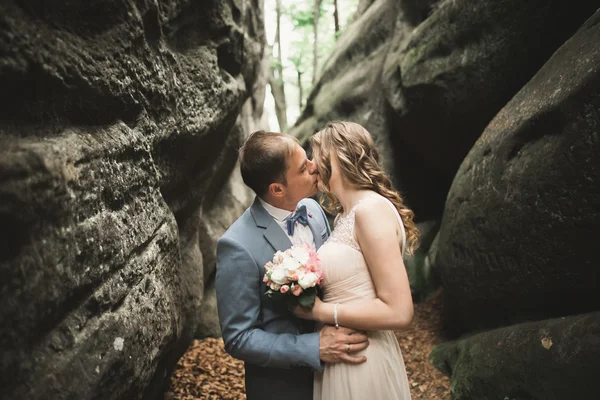 Splendido matrimonio coppia baci e abbracci nella foresta con grandi rocce — Foto Stock