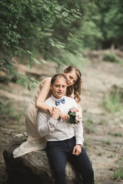 Elegante noivo elegante doce e noiva perto do rio com pedras. Casamento casal apaixonado — Fotografia de Stock