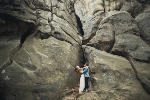 Счастливая супружеская пара целуется и обнимается у высокой скалы — стоковое фото