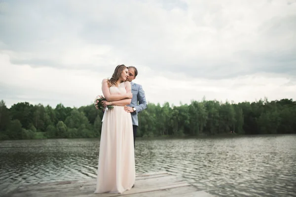 Novia y novio caminando por el río, sonriendo, besando — Foto de Stock