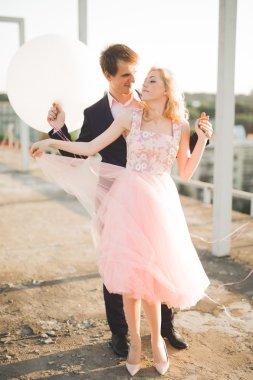 Çatıda mükemmel şehir manzaralı elele ve sarılma poz aşık genç bir çift. Güzel gün batımı