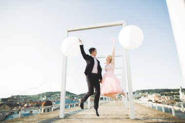 Sevgi dolu çift atlama ve eski şehir'in backgrounf ile çatı üzerinde gülümseyen