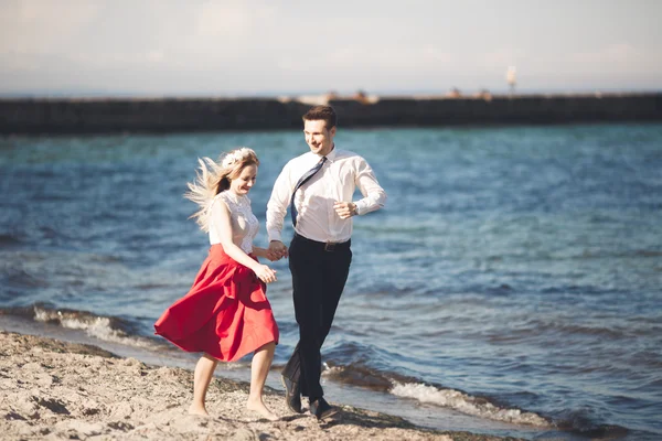 Giovane coppia felice che cammina sulla spiaggia sorridendo abbracciati l'un l'altro. Storia d'amore — Foto Stock