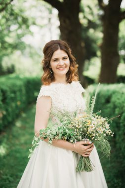 Parkta poz veren gelinlikli güzel, lüks bir gelin.