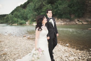 Gelin ve damat güzel düğün buket tutarak. Nehir kenarında poz