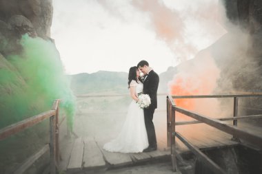 Çift yakınındaki kayaların arkasında renkli duman ile poz düğün