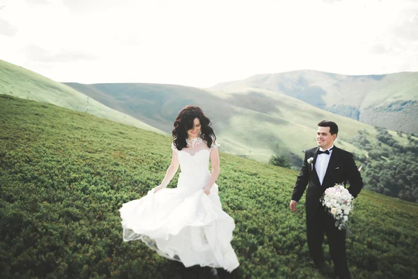 Сказочно счастливая невеста и стильный жених, позирующий на фоне солнечных потрясающих гор — стоковое фото