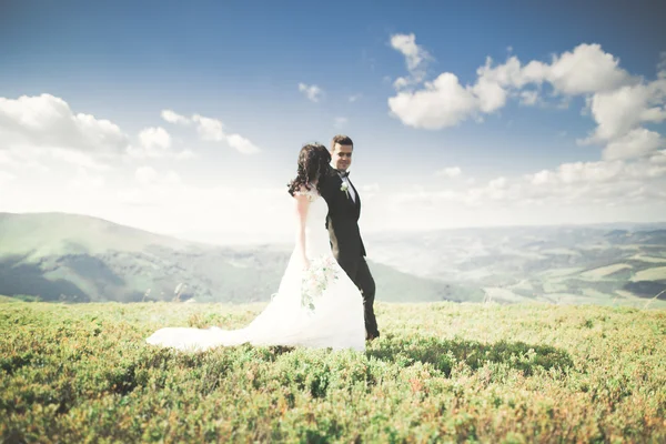 Bella favolosa sposa felice ed elegante sposo in posa sullo sfondo delle montagne soleggiate mozzafiato — Foto Stock